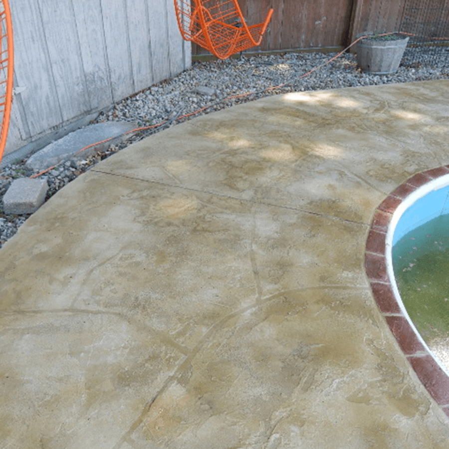 A decorative concrete patio with a swimming pool in the background