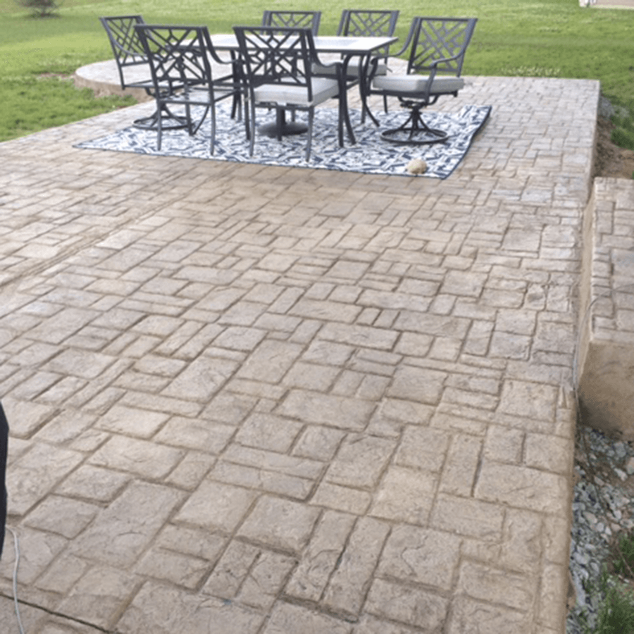 A decorative concrete patio with a table and chairs on it