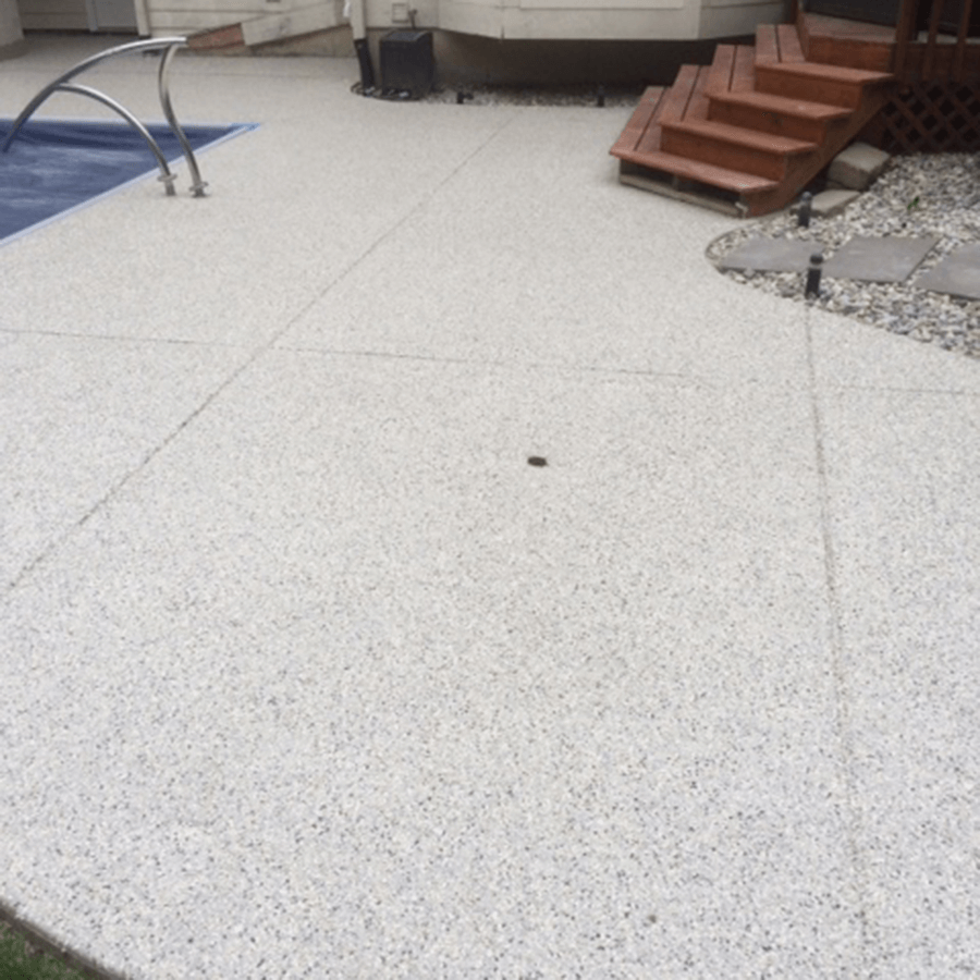 A concrete patio with stairs and a pool in the background