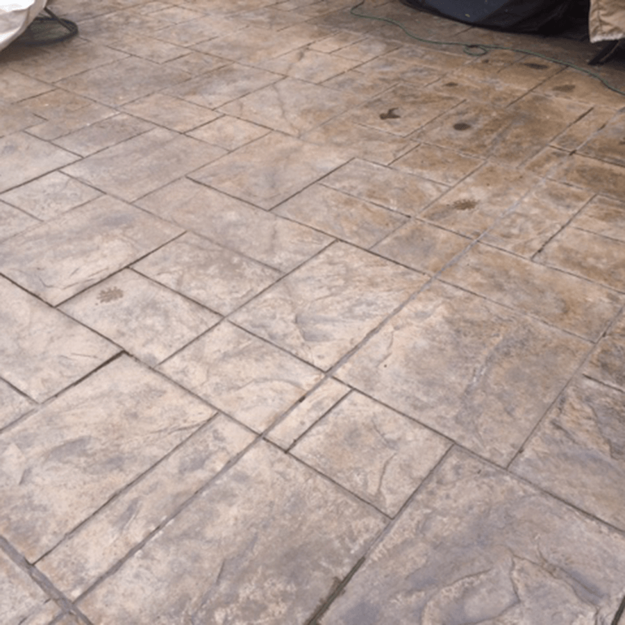 A close up of a decorative concrete floor with a motorcycle cover on it.