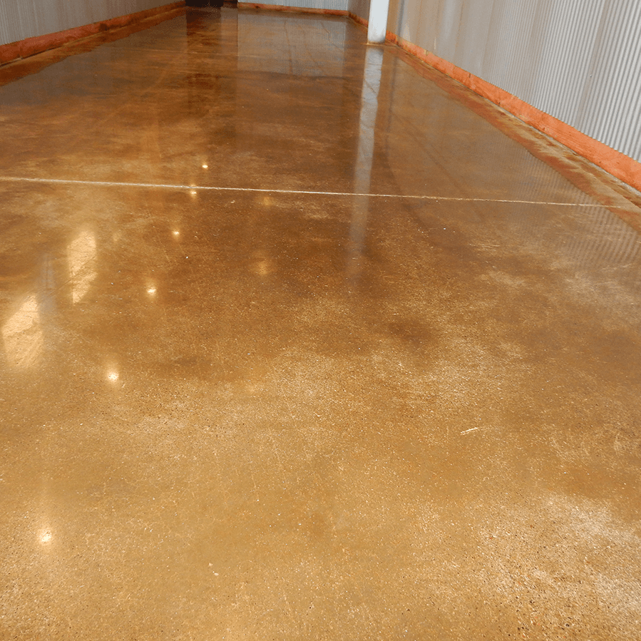 A shiny concrete floor in a hallway with a white wall