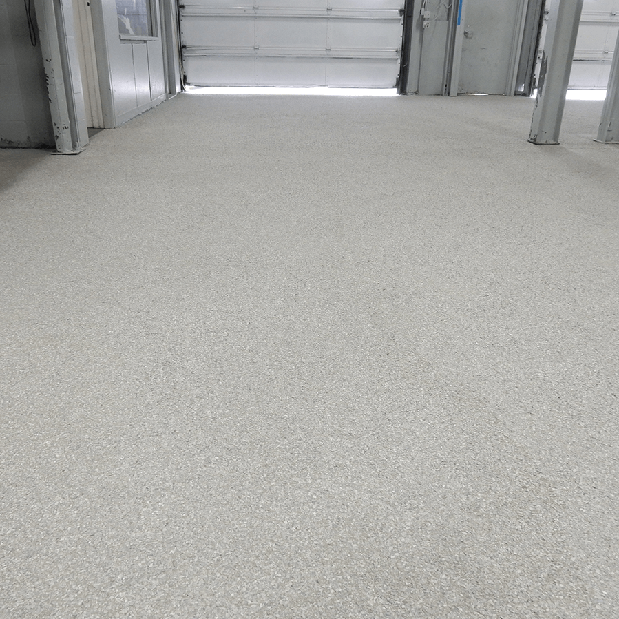 A concrete garage floor with a garage door in the background.