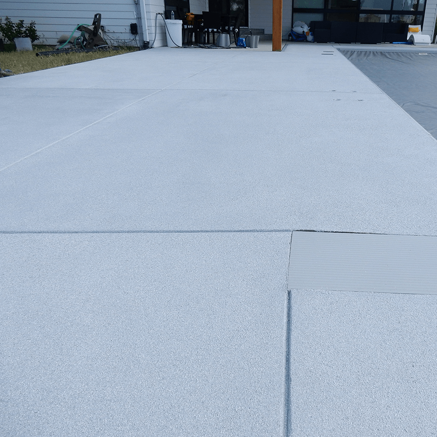 A white concrete walkway next to a swimming pool