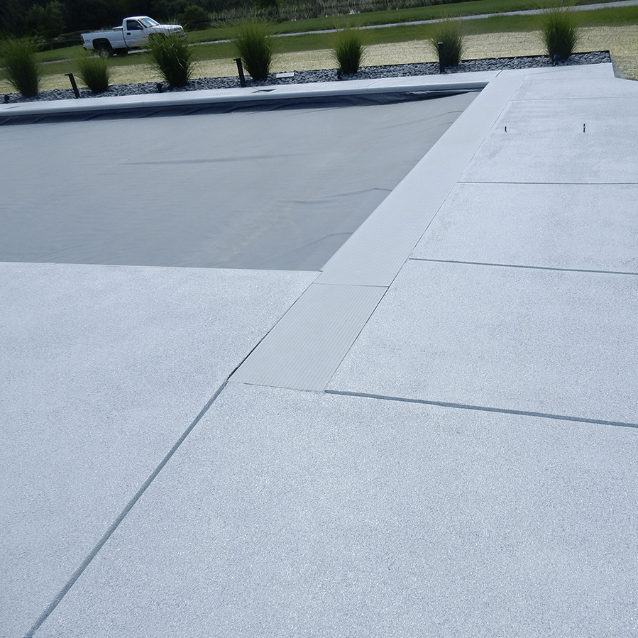 A white concrete walkway next to a swimming pool