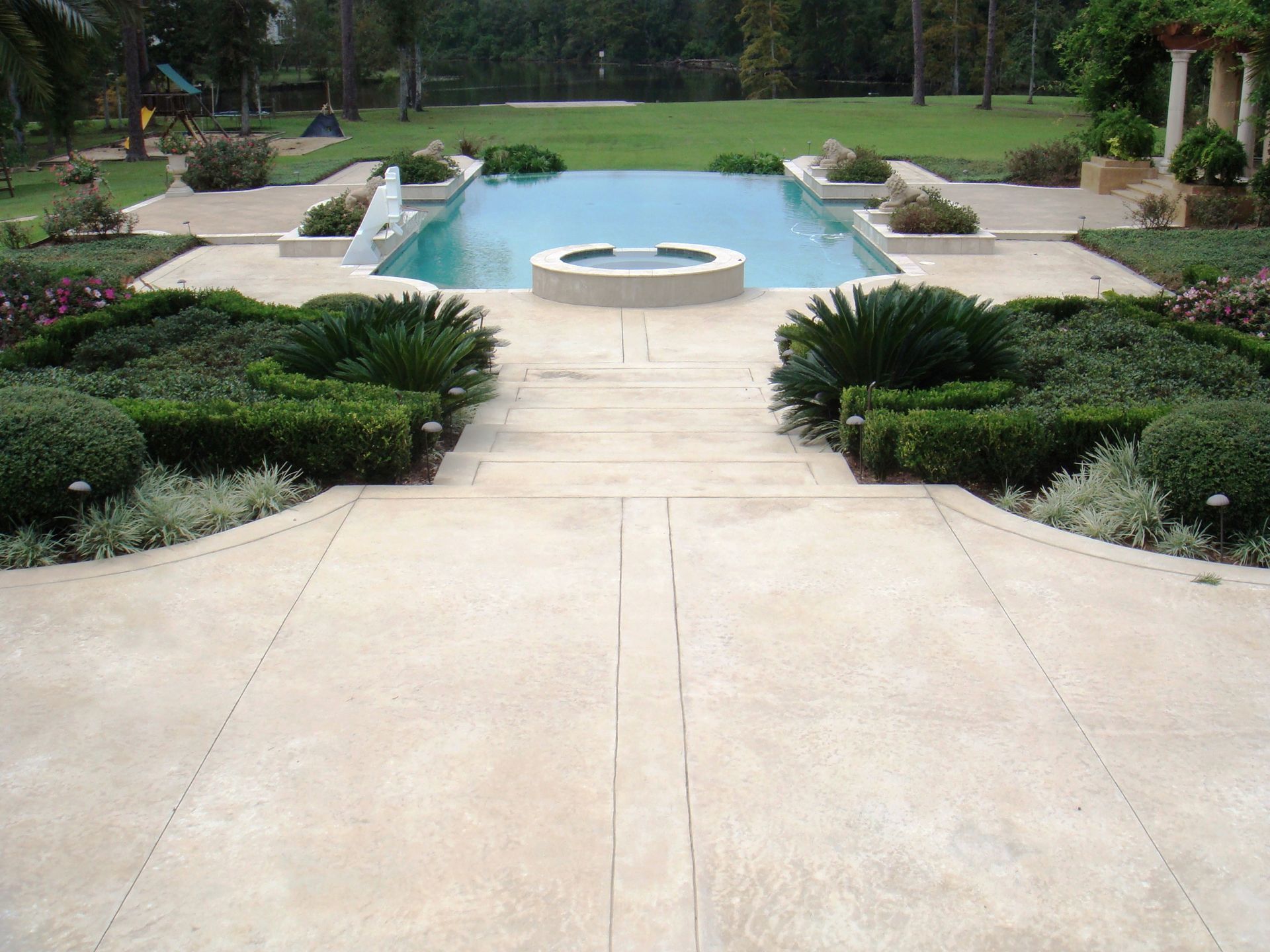 A large swimming pool with a hot tub in the middle and decorative concrete floor