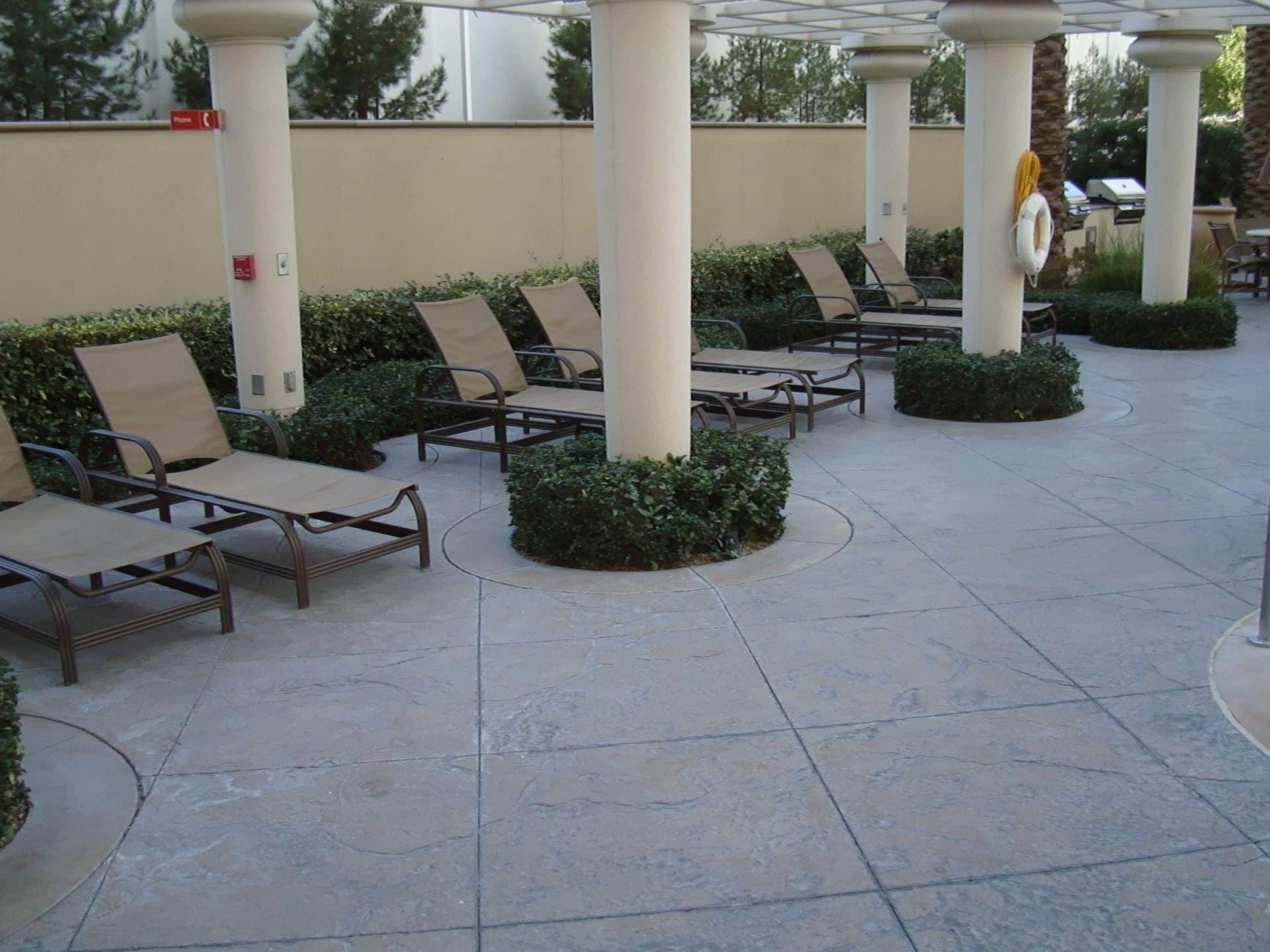 A patio with chairs and columns and a life preserver on a stamped concrete floor