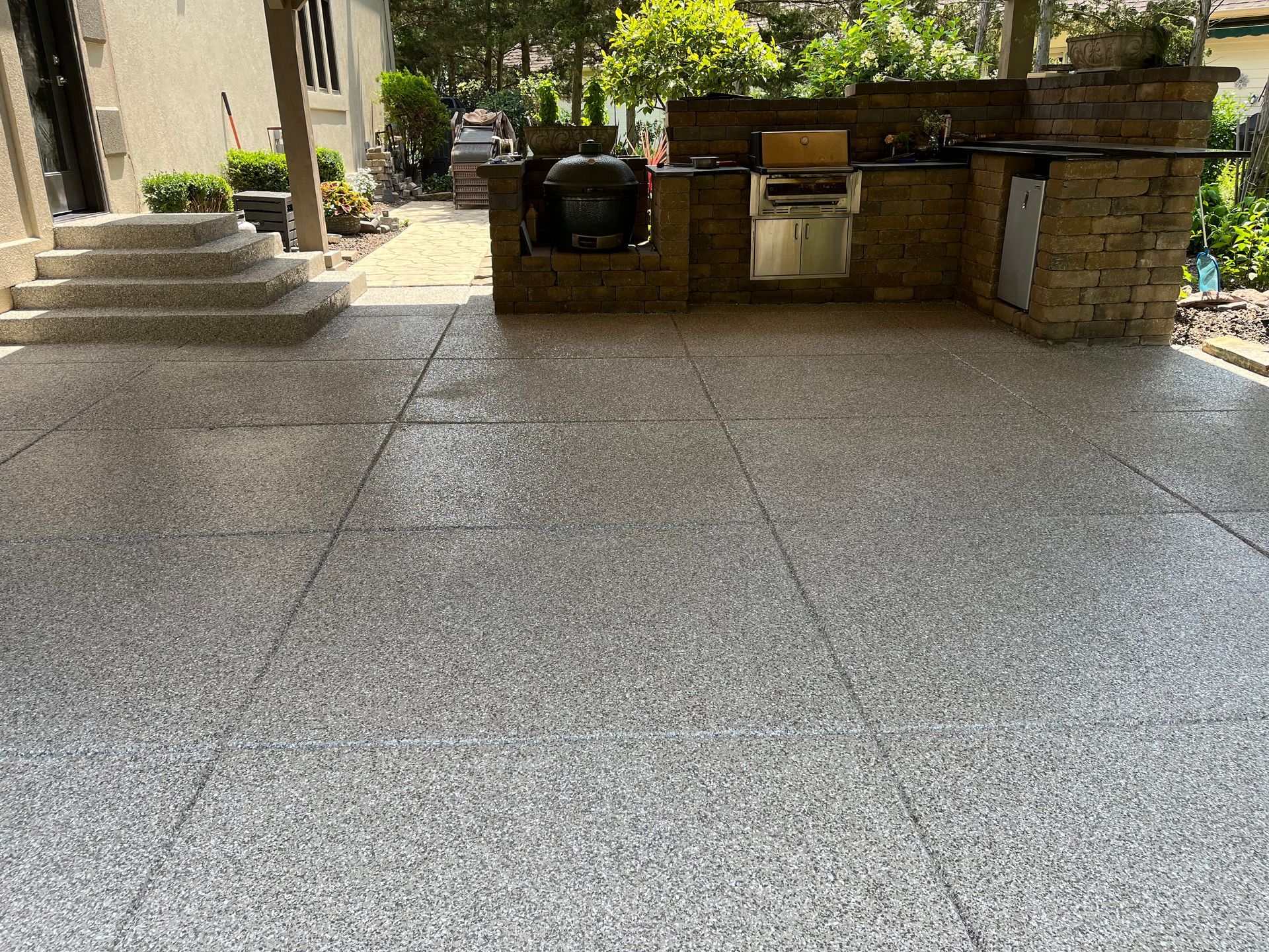 A patio with a kitchen and a grill on gray tiled floor