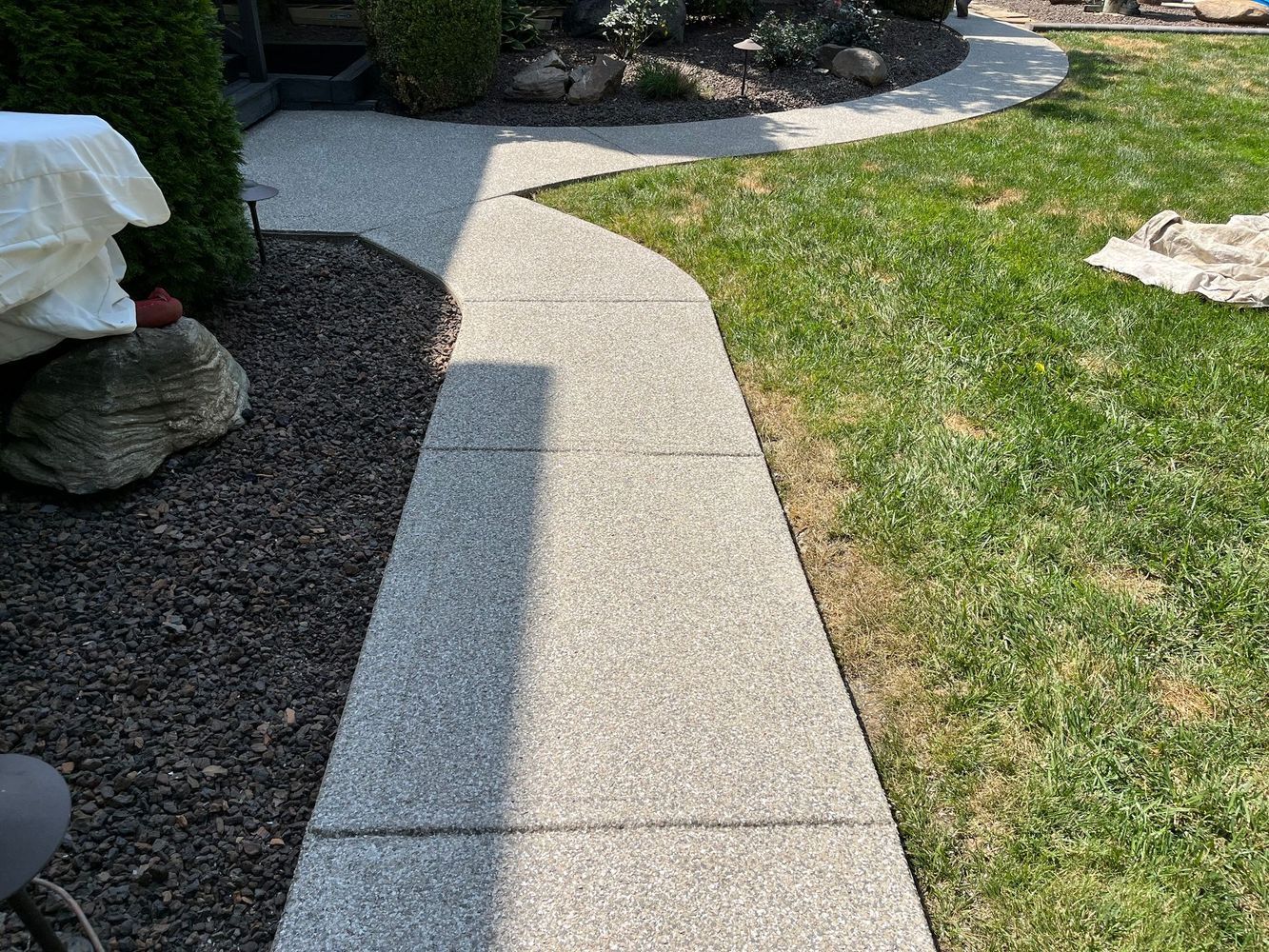 A concrete walkway going through a lush green yard.