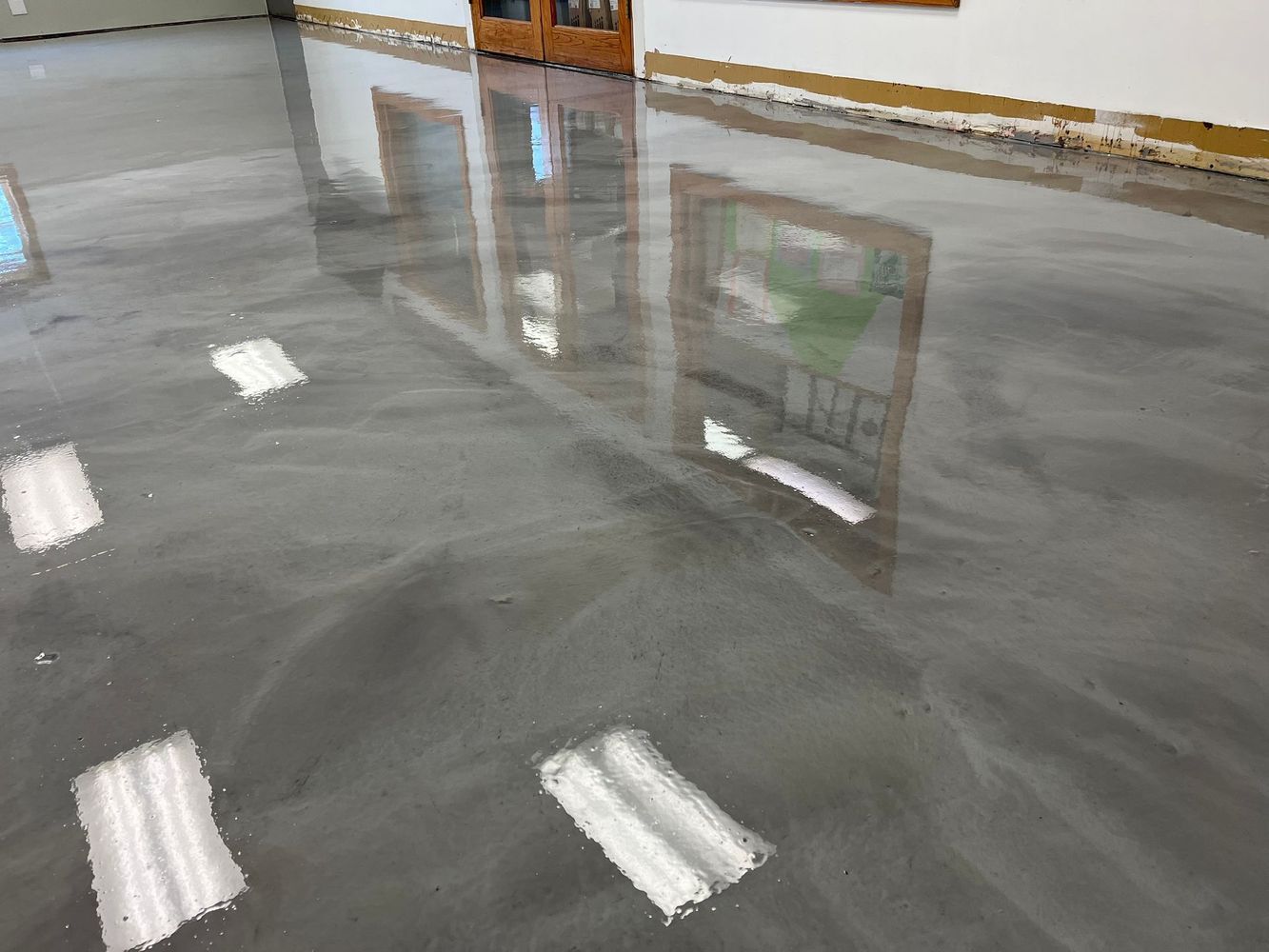 A shiny concrete floor with a reflection of a window in it.