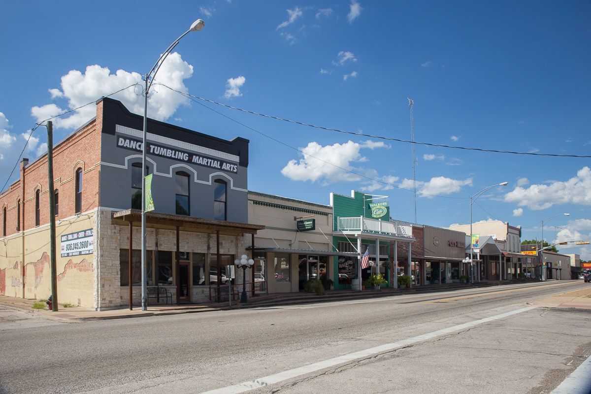 A row of buildings are lined up on the side of a road.