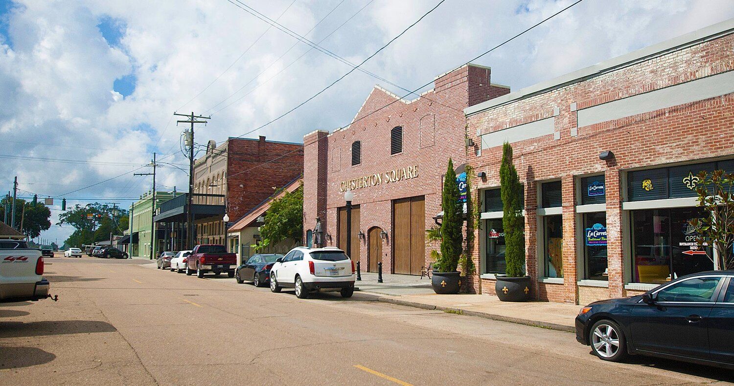 A row of brick buildings with cars parked on the side of the road.