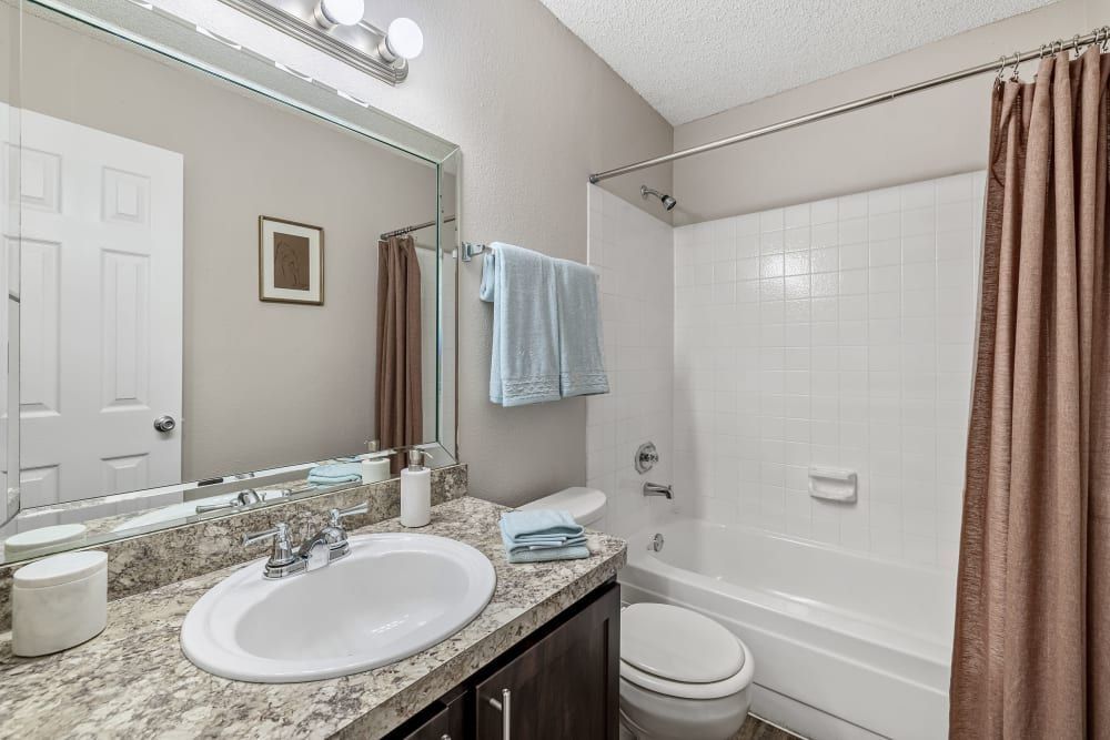 a bathroom with a sink , toilet , tub and mirror at The Park at Flower Mound in Flower Mound, TX.