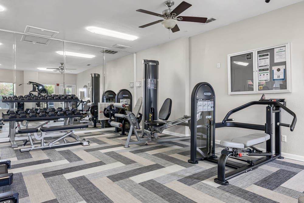 a gym with a lot of exercise equipment and a ceiling fan at The Park at Flower Mound in Flower Mound, TX.