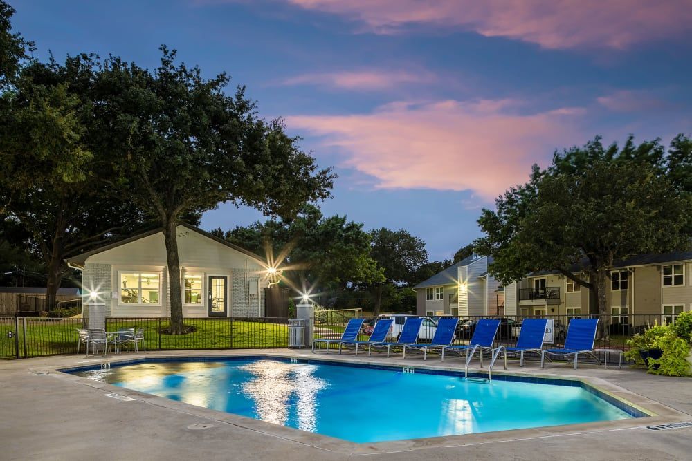 a large swimming pool with blue chairs and a house in the background at The Park at Flower Mound in Flower Mound, TX.