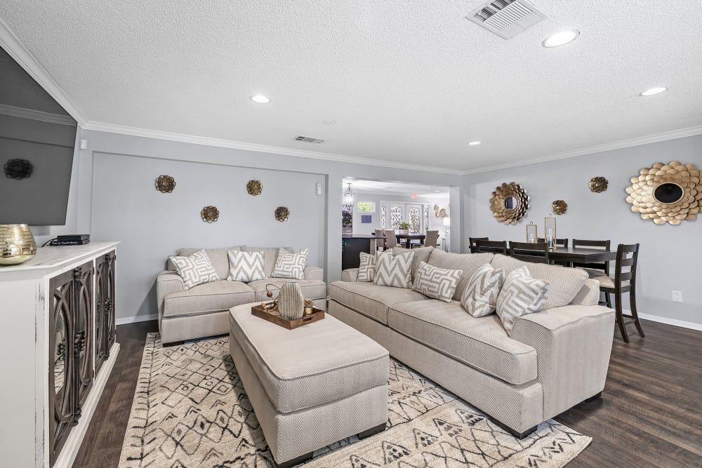 a living room with a couch , ottoman , and television at The Park at Flower Mound in Flower Mound, TX.