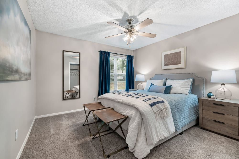a bedroom with a bed , nightstand , mirror and ceiling fan at The Park at Flower Mound in Flower Mound, TX.