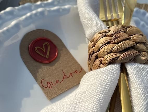 Place setting with a name card, napkin ring, and gold silverware on a white plate.