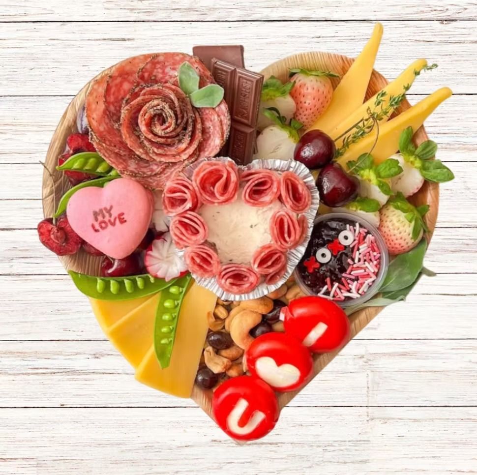 Heart-shaped charcuterie board with salami roses, cheeses, fruits, nuts, chocolates, and 