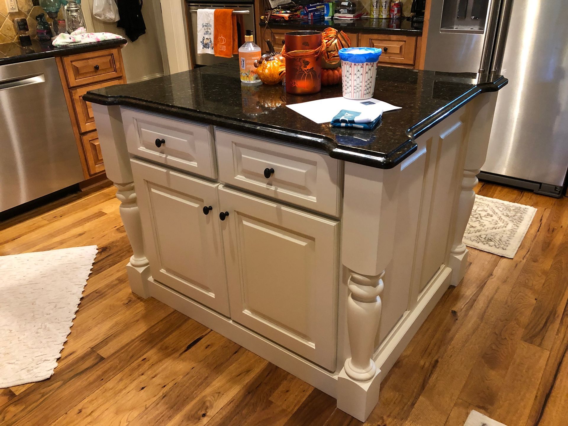 A kitchen island with black granite counter tops and white cabinets.