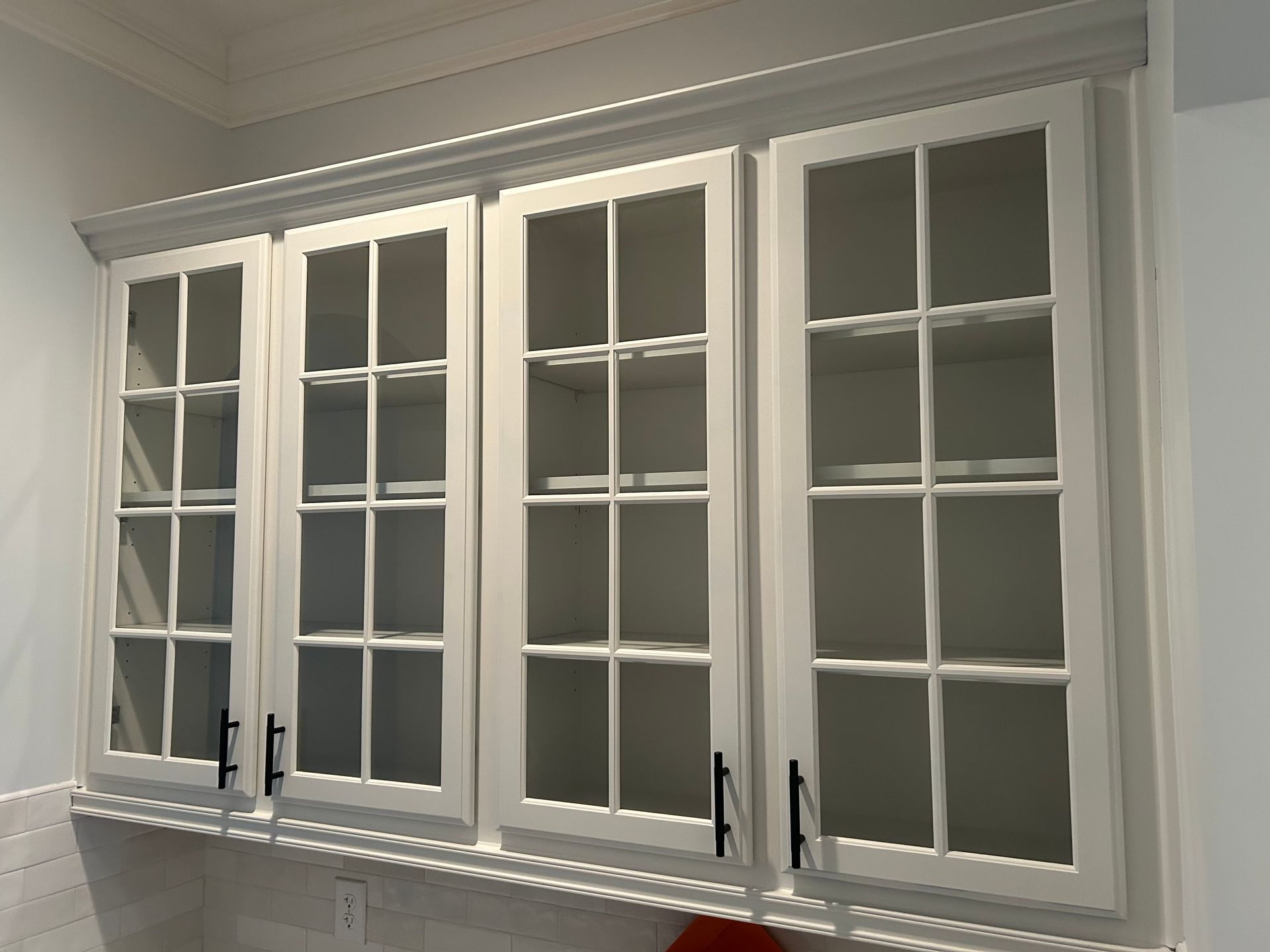 A kitchen with white cabinets and glass doors