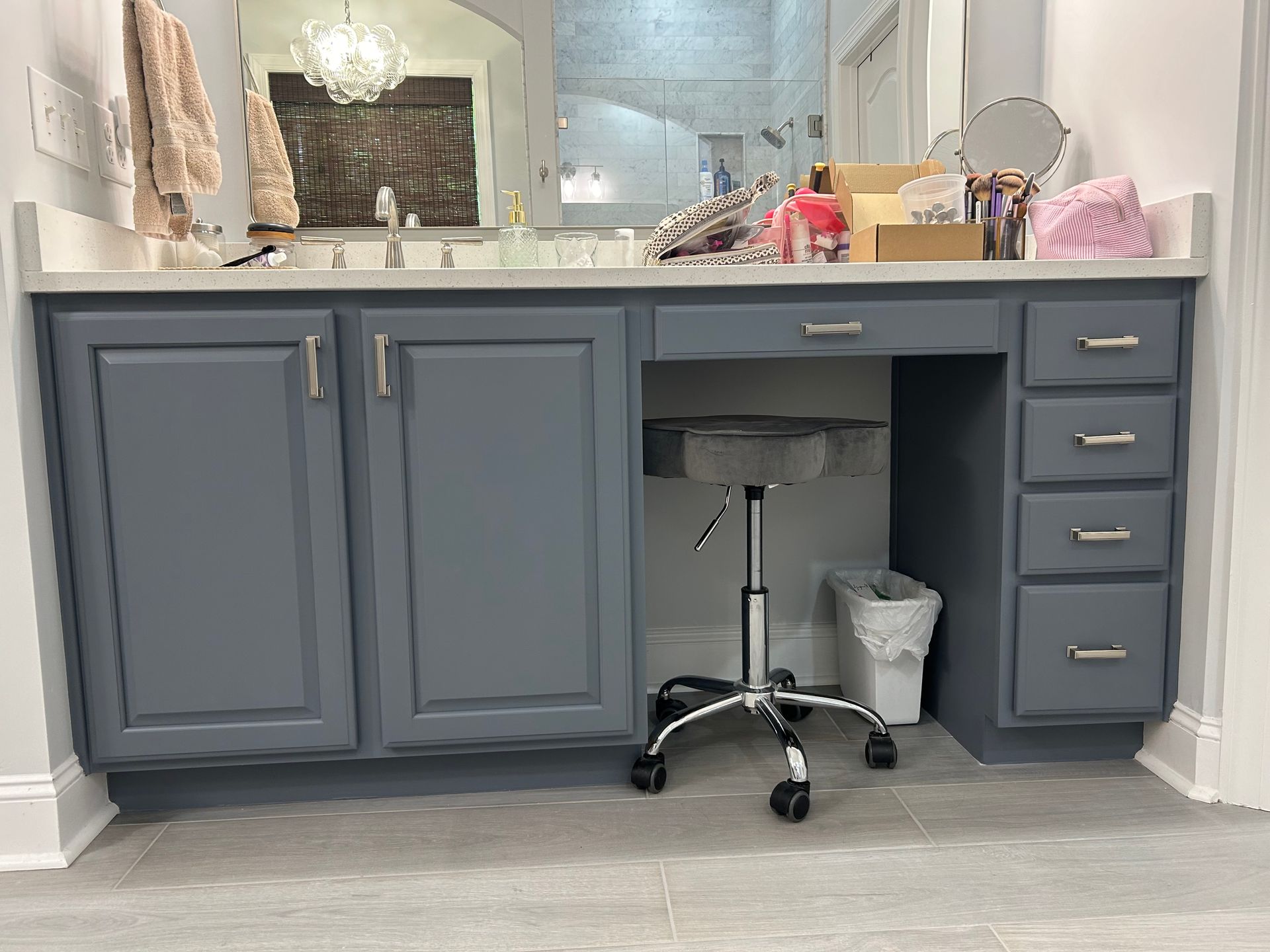 A bathroom vanity with a desk and chair underneath it.