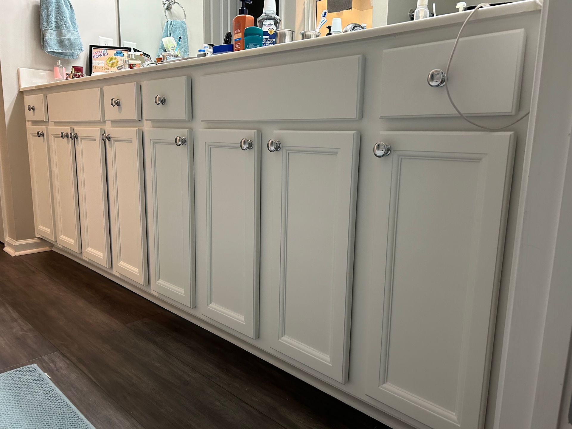 A bathroom with white cabinets and a large mirror.
