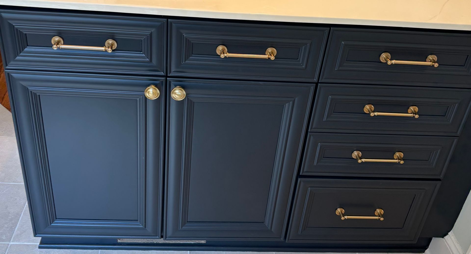 Dark blue bathroom vanity with gold hardware and a light countertop.