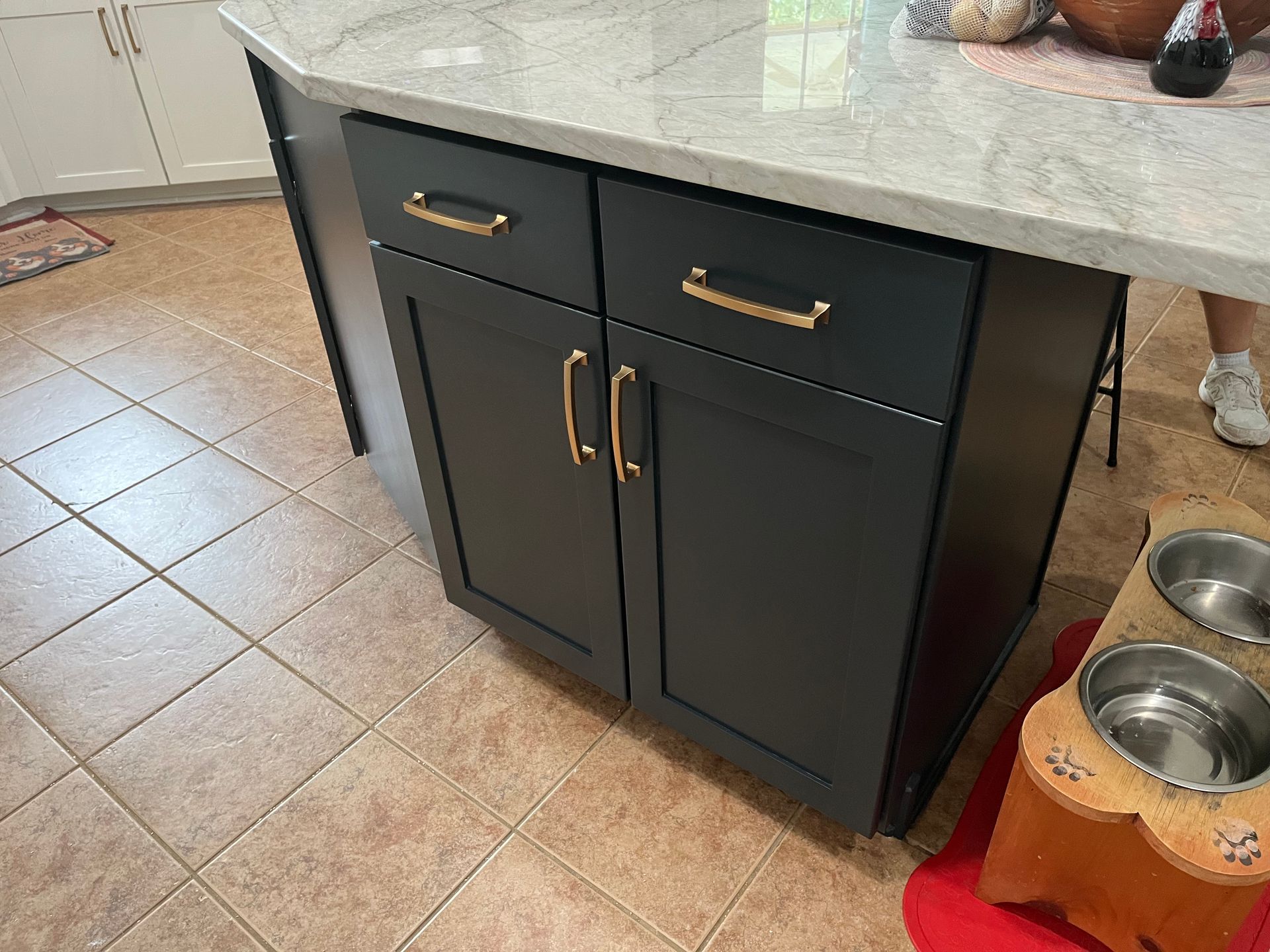 A kitchen island with black cabinets and a marble counter top.