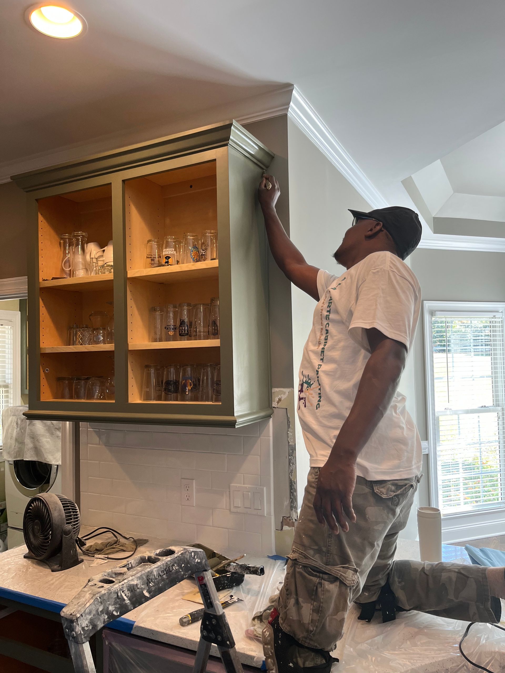 A man is painting a cabinet in a kitchen.