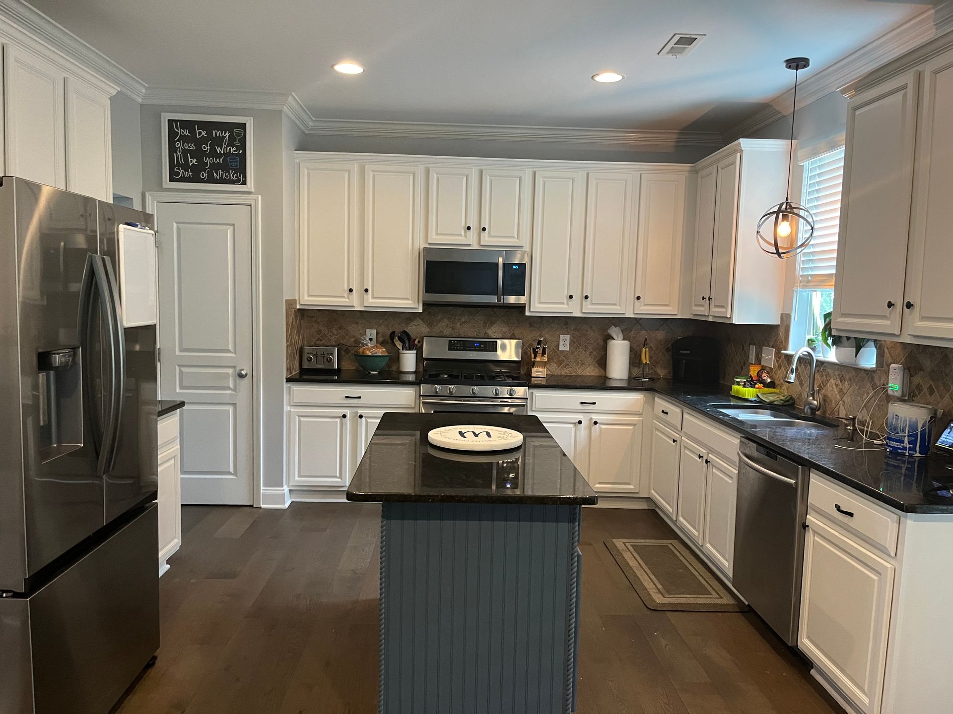 A kitchen with white cabinets , stainless steel appliances , and a large island.