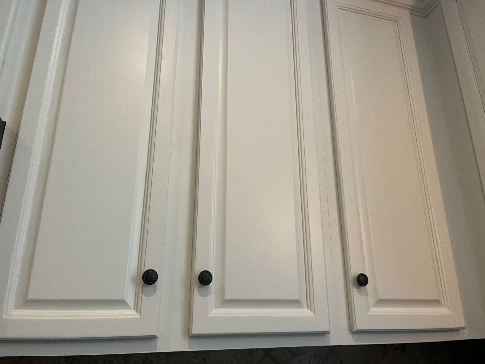 A row of white cabinet doors with black knobs