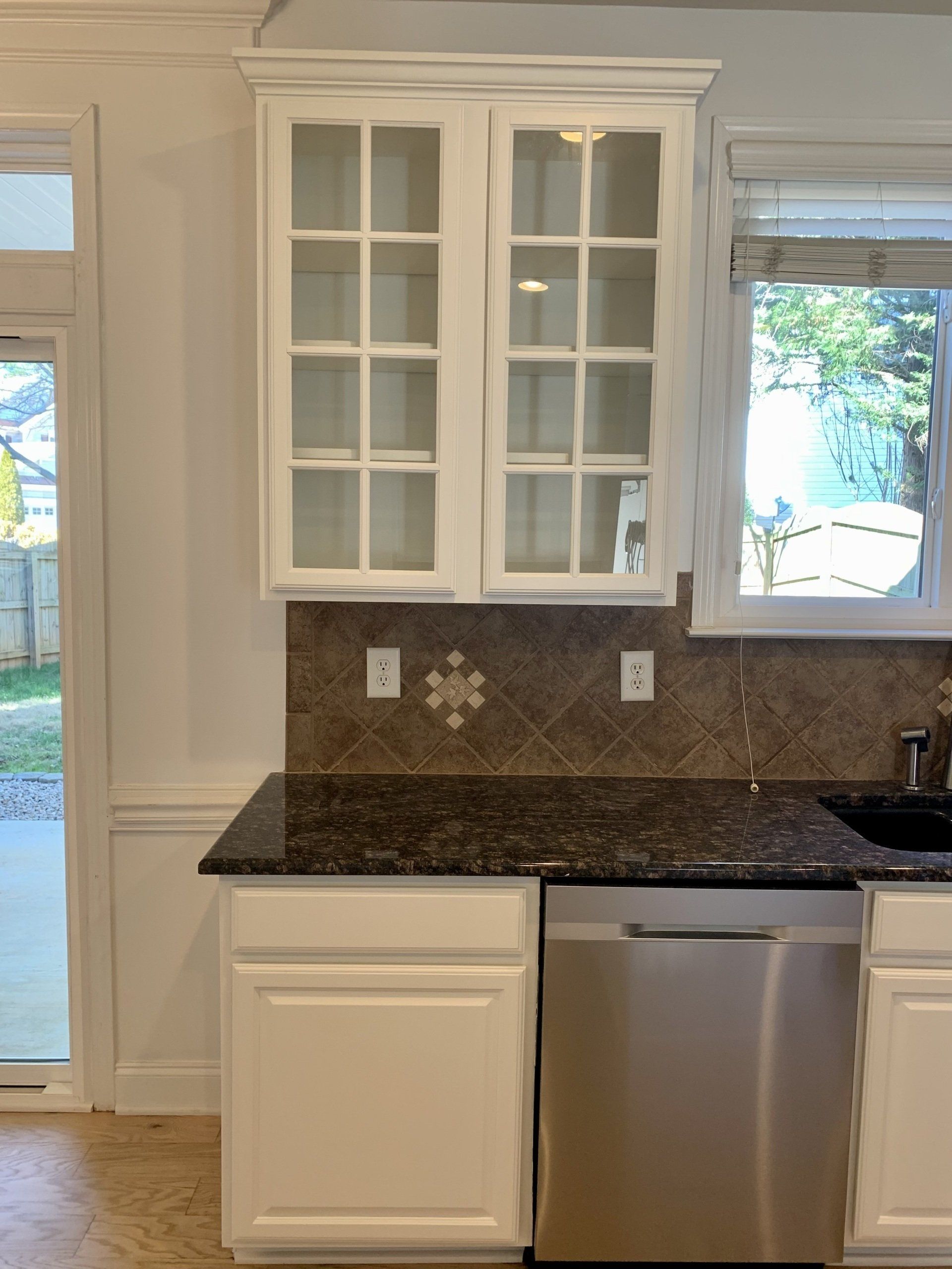 A kitchen with white cabinets and a stainless steel dishwasher