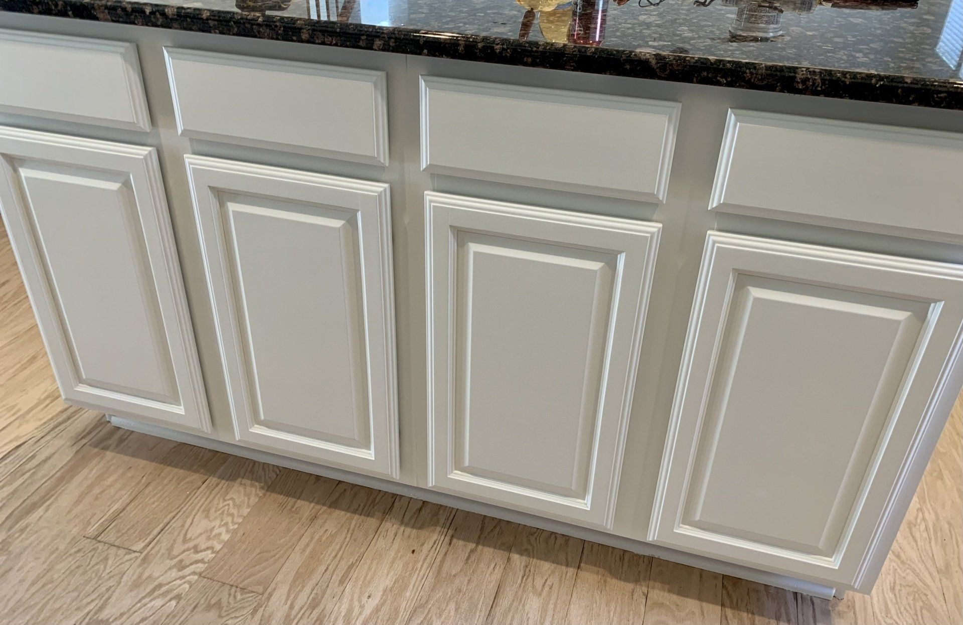 A kitchen island with white cabinets and a granite counter top.