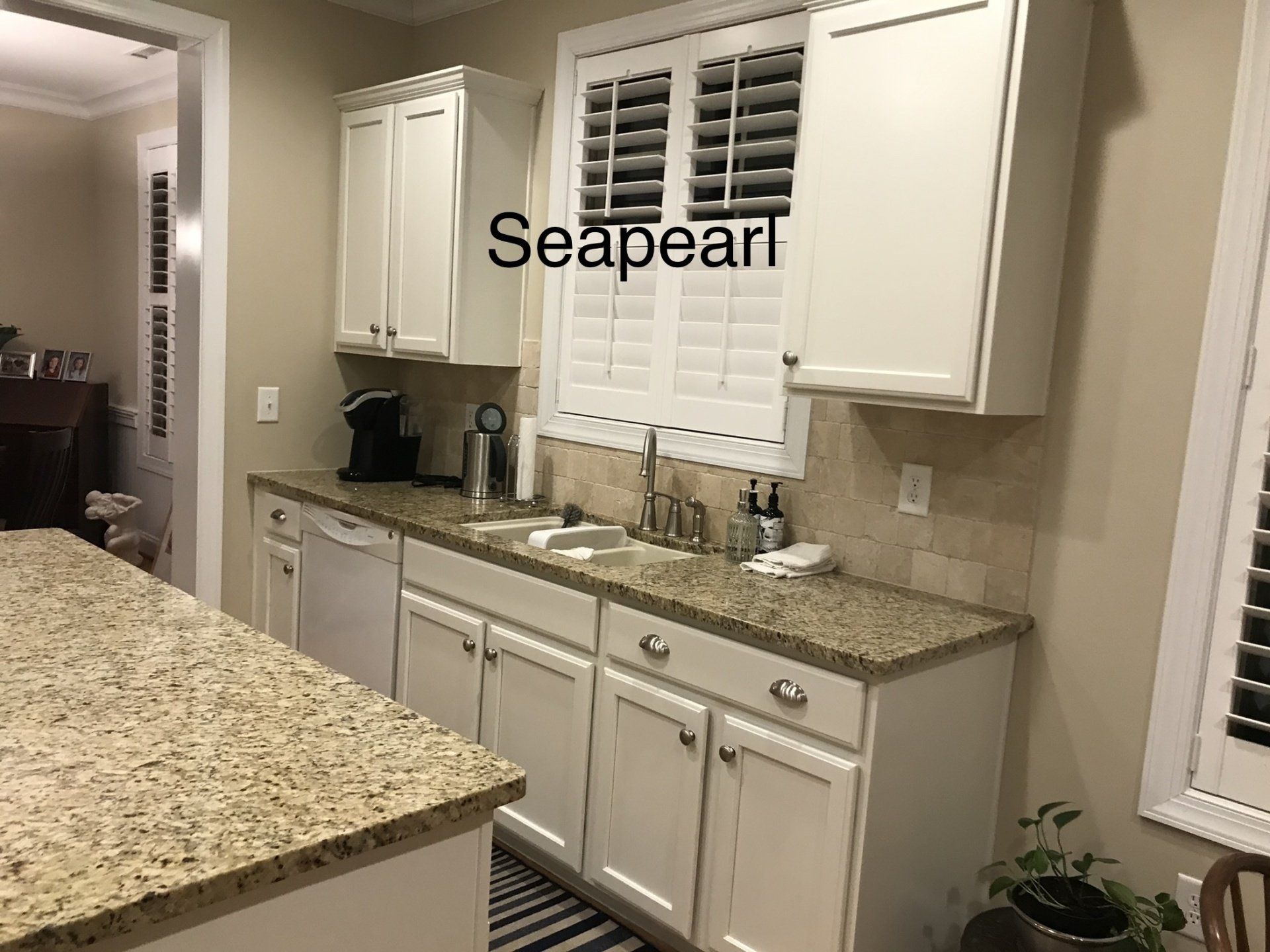 A kitchen with white cabinets and granite counter tops and the words seapearl on the bottom
