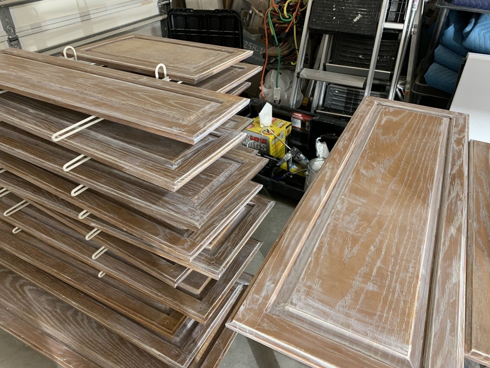 A stack of wooden cabinet doors sitting on top of each other in a garage.