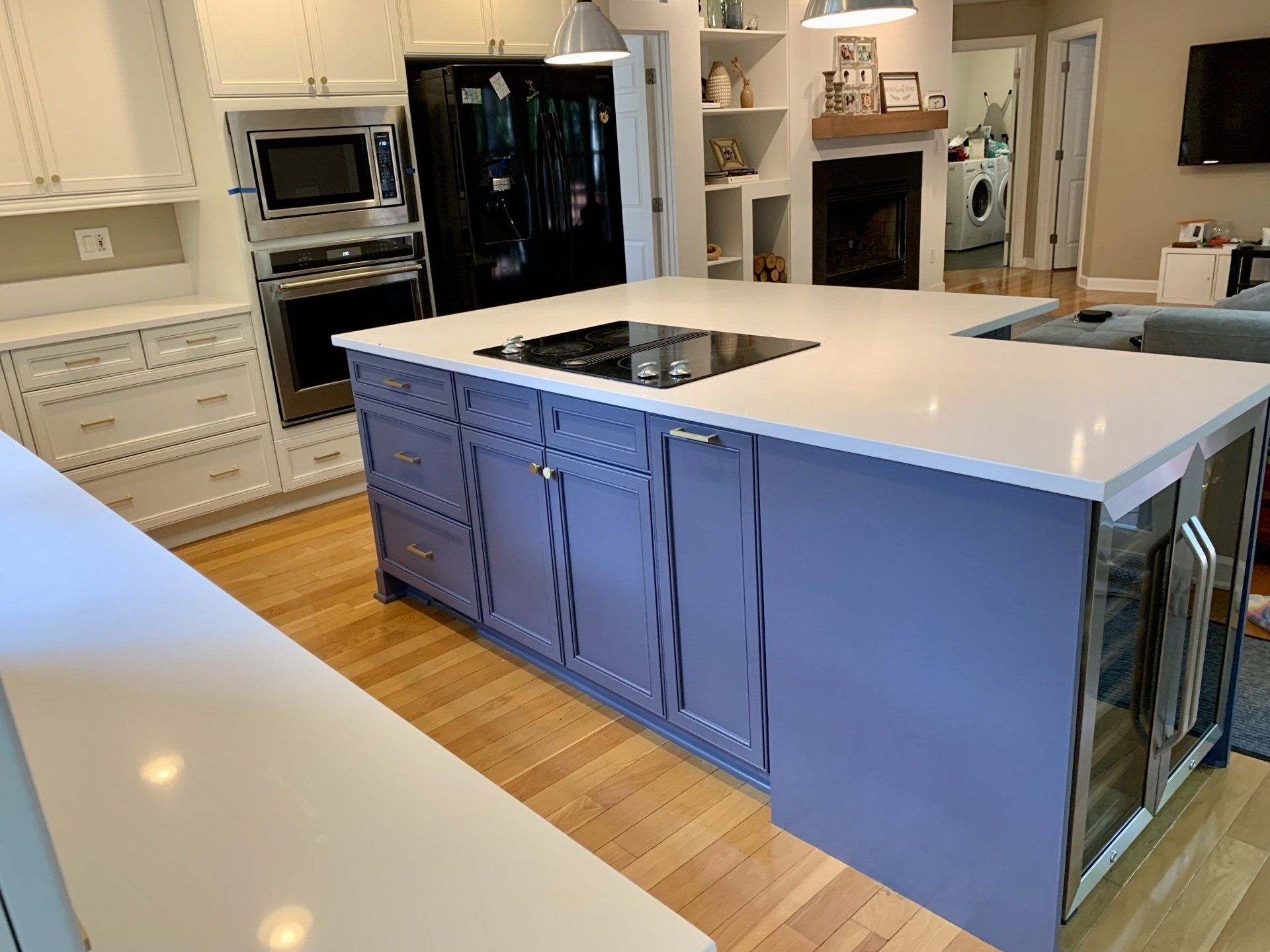 A kitchen with purple cabinets and a large island with a stove top oven.
