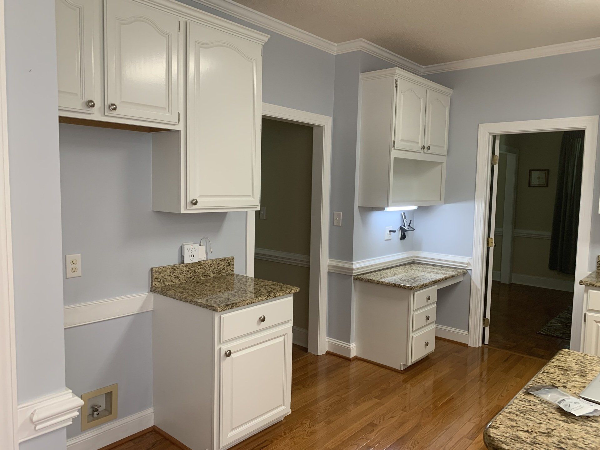 A kitchen with white cabinets and granite counter tops.