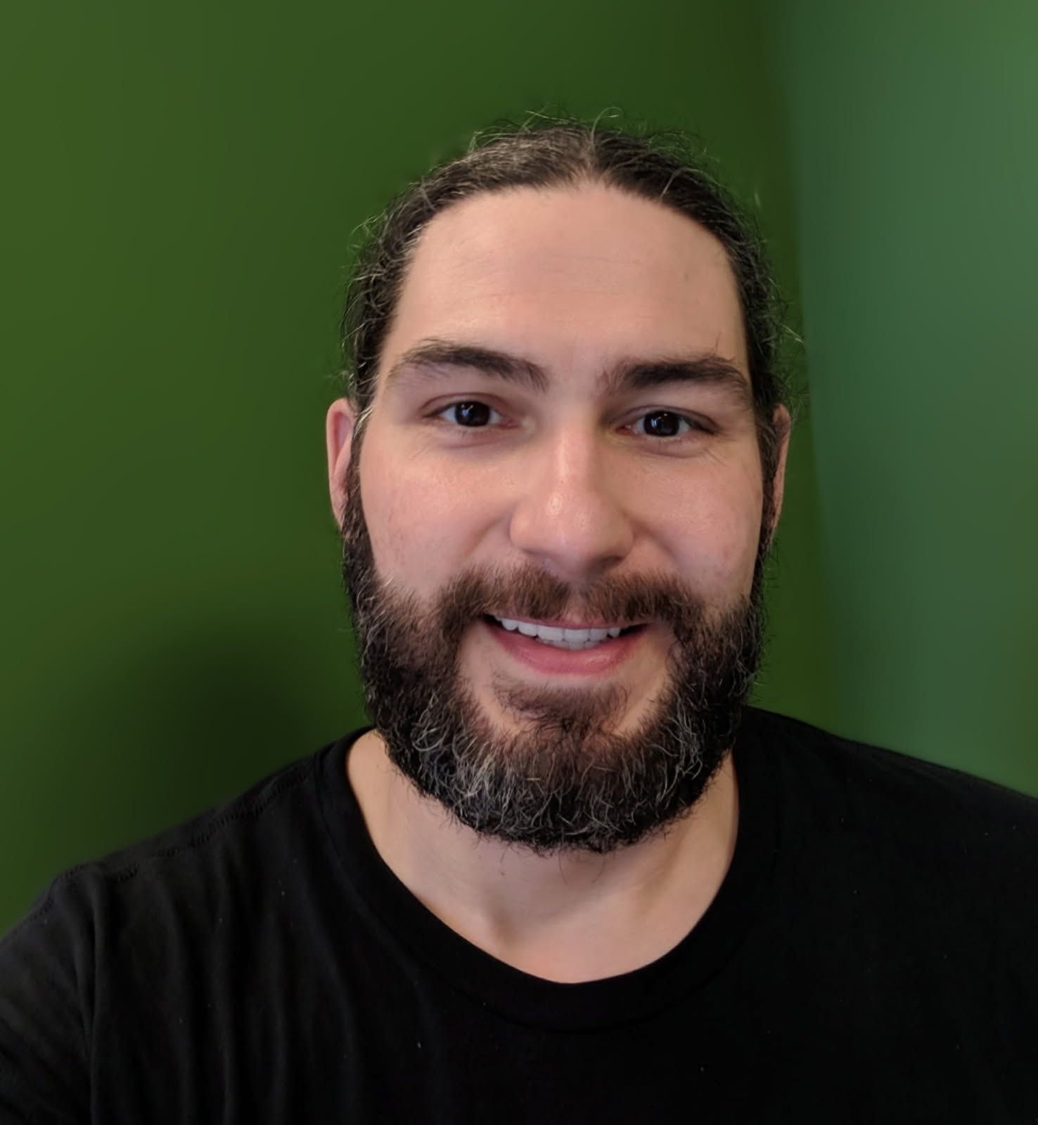 A man with a beard and long hair is smiling for the camera.