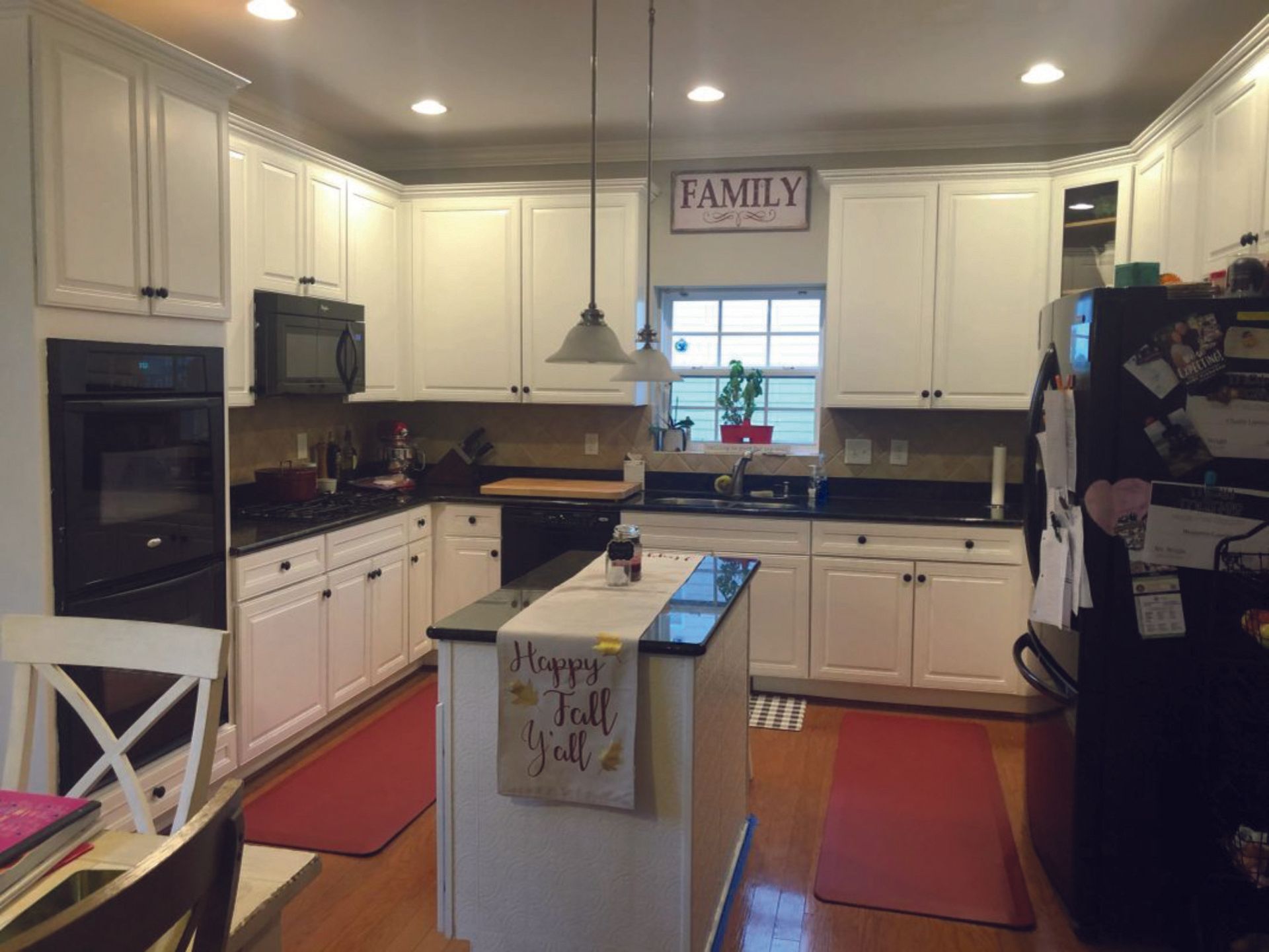 A kitchen with white cabinets and a sign that says family