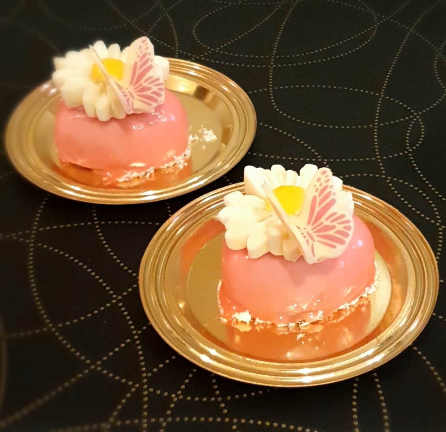 Due piatti di torte rosa con farfalle sopra