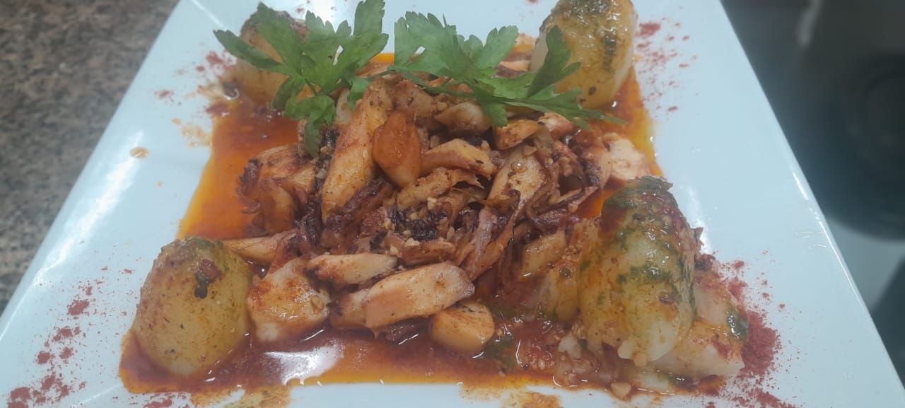 Cocina moderna con anafe de color negro, horno, microondas y gabinetes de color rojo y marrón.