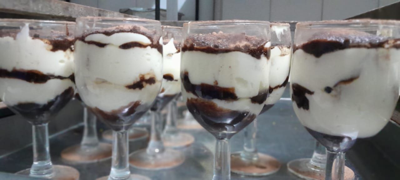 Cocina moderna con isla de granito y refrigerador empotrado. Muebles blancos y suelo de mármol.