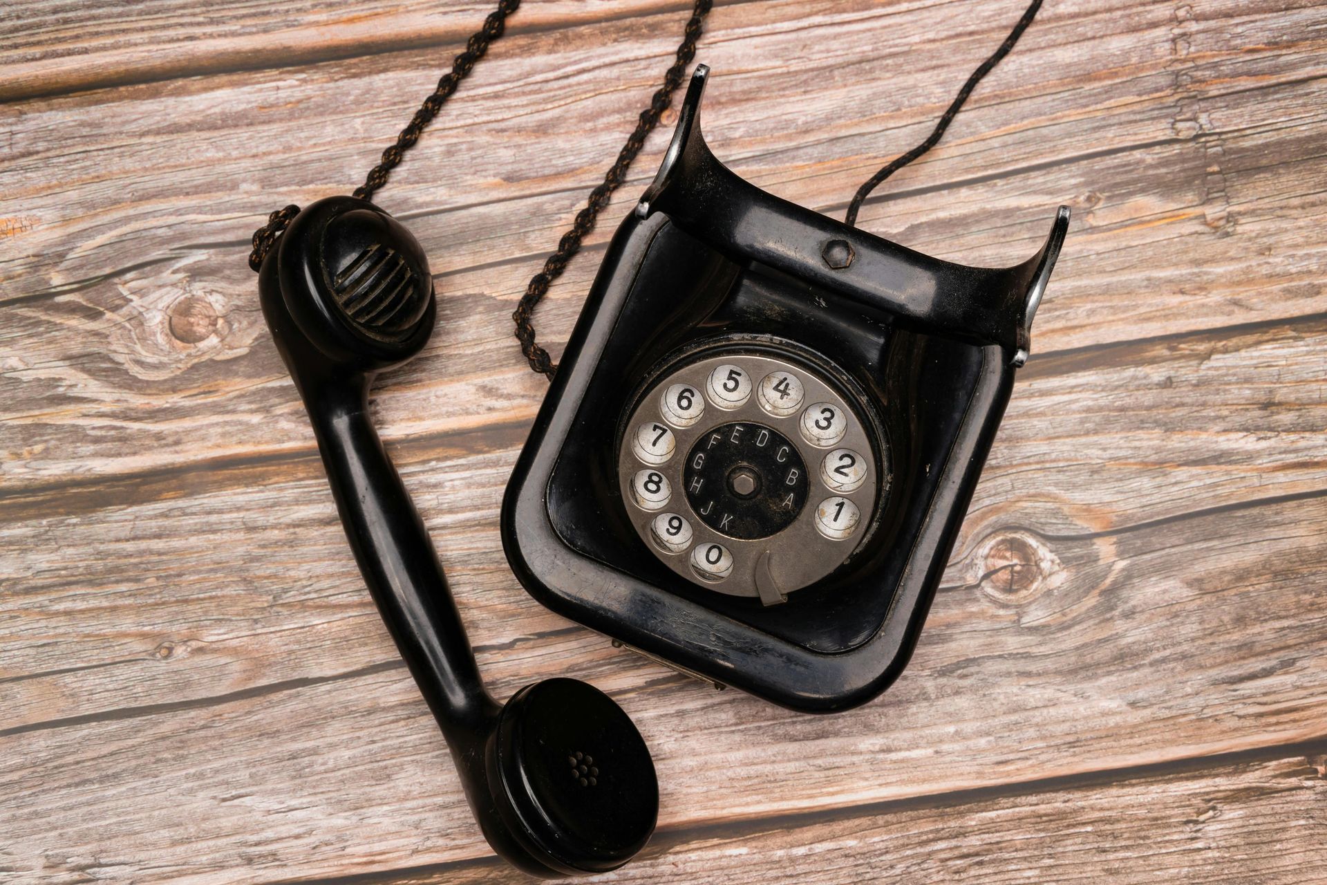 An old black telephone is sitting on a wooden table.