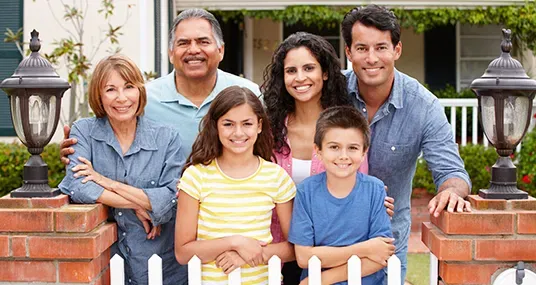 Family of six smiling together in front of their home.