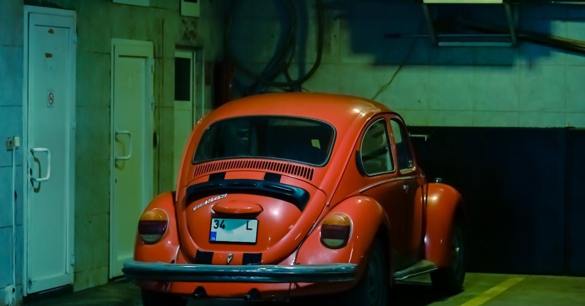 A red beetle is parked in a garage next to a door.