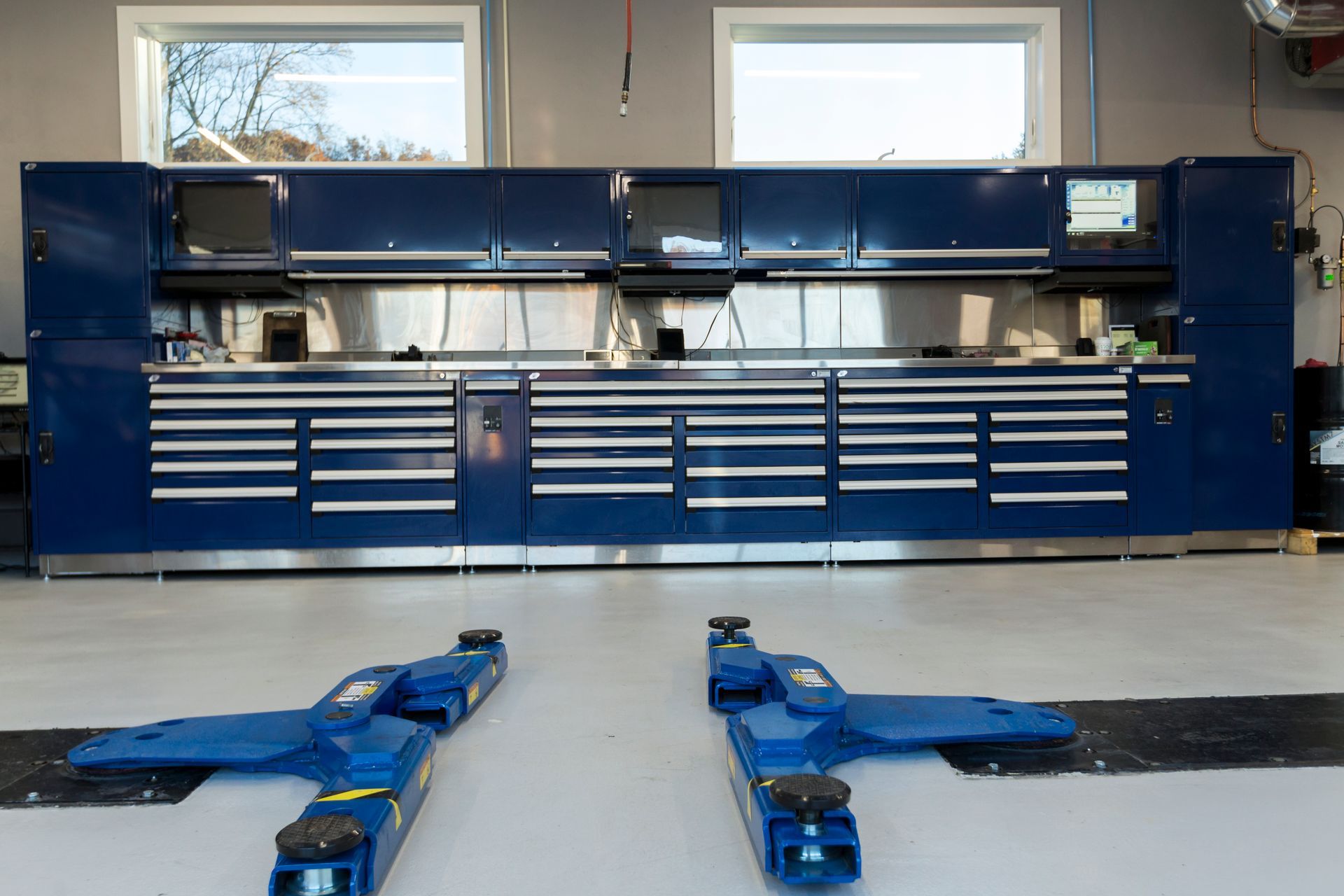 Blue mechanic's toolboxes and workstation in a garage, with two car lifts on the floor. | Plandome Service Center