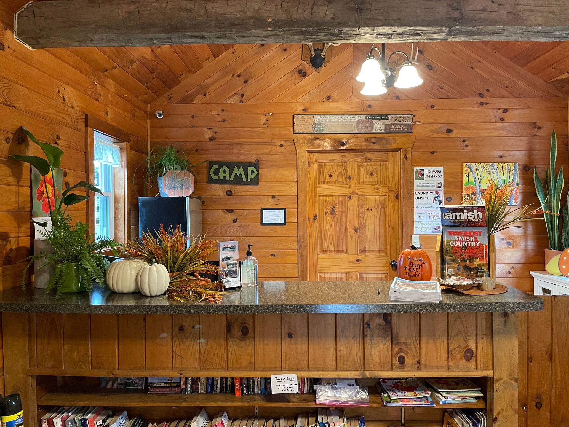 Gravel driveway leads toward trees, flanked by brown fences and American flags.
