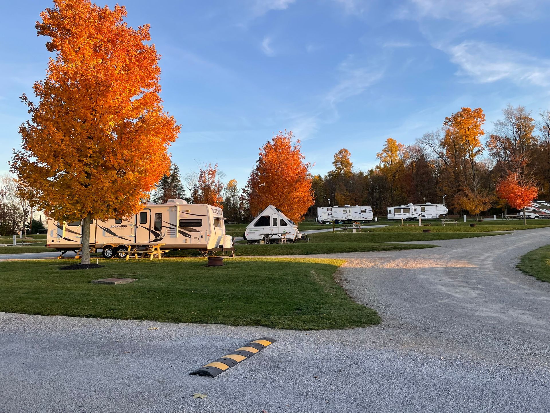 Gravel RV park road with parked RVs on either side, sunny day.