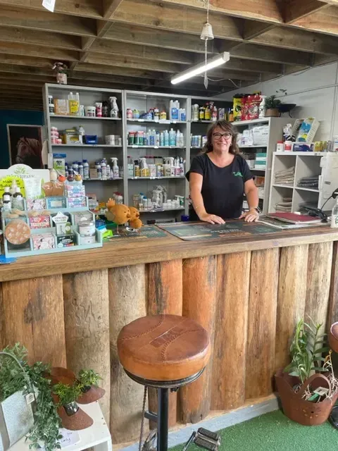 A Woman Is Standing Behind a Wooden Counter in A Store — Yeppoon Stockfeed & Rural Supplies in Yeppoon, QLD