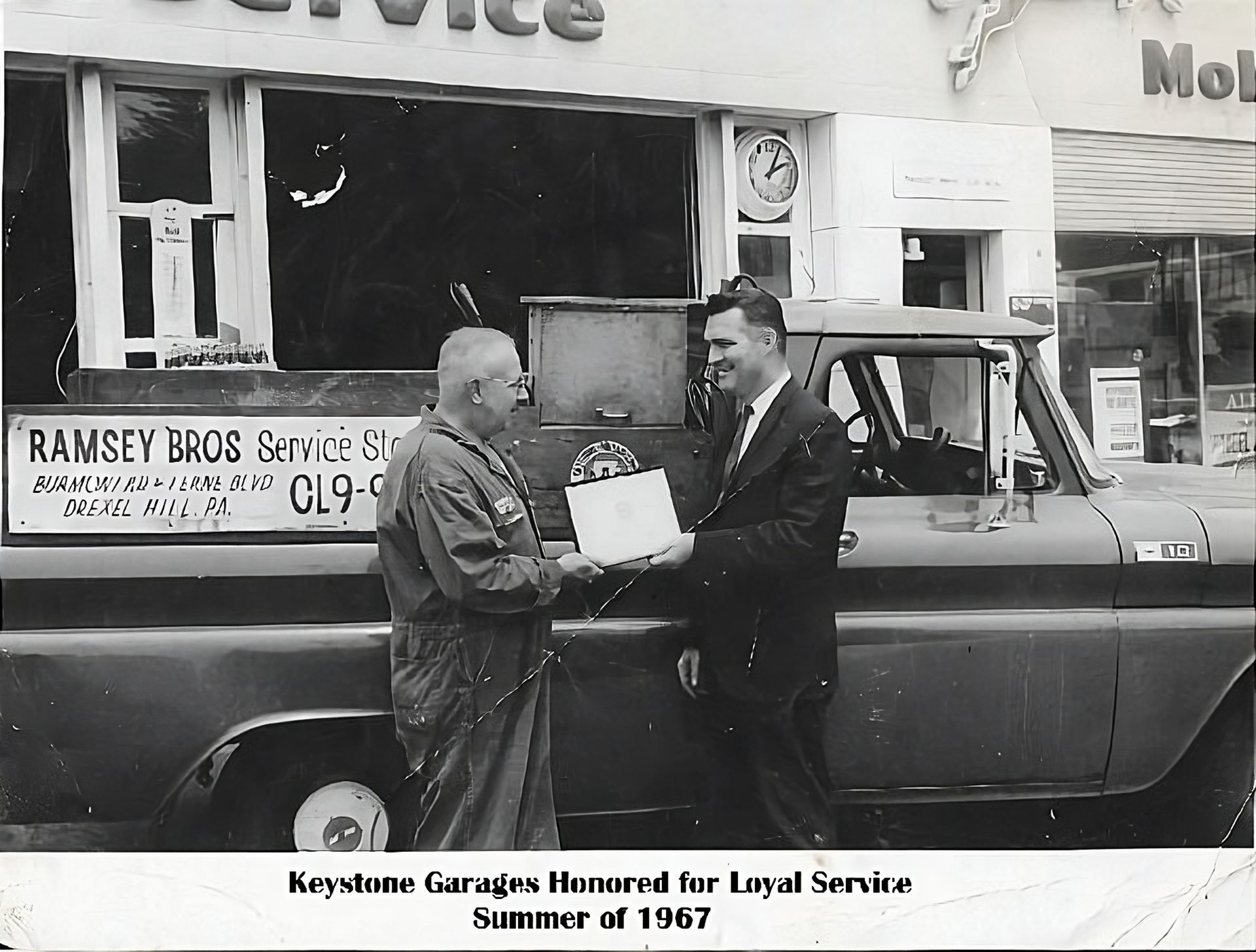 Two men exchanging documents by a service truck,